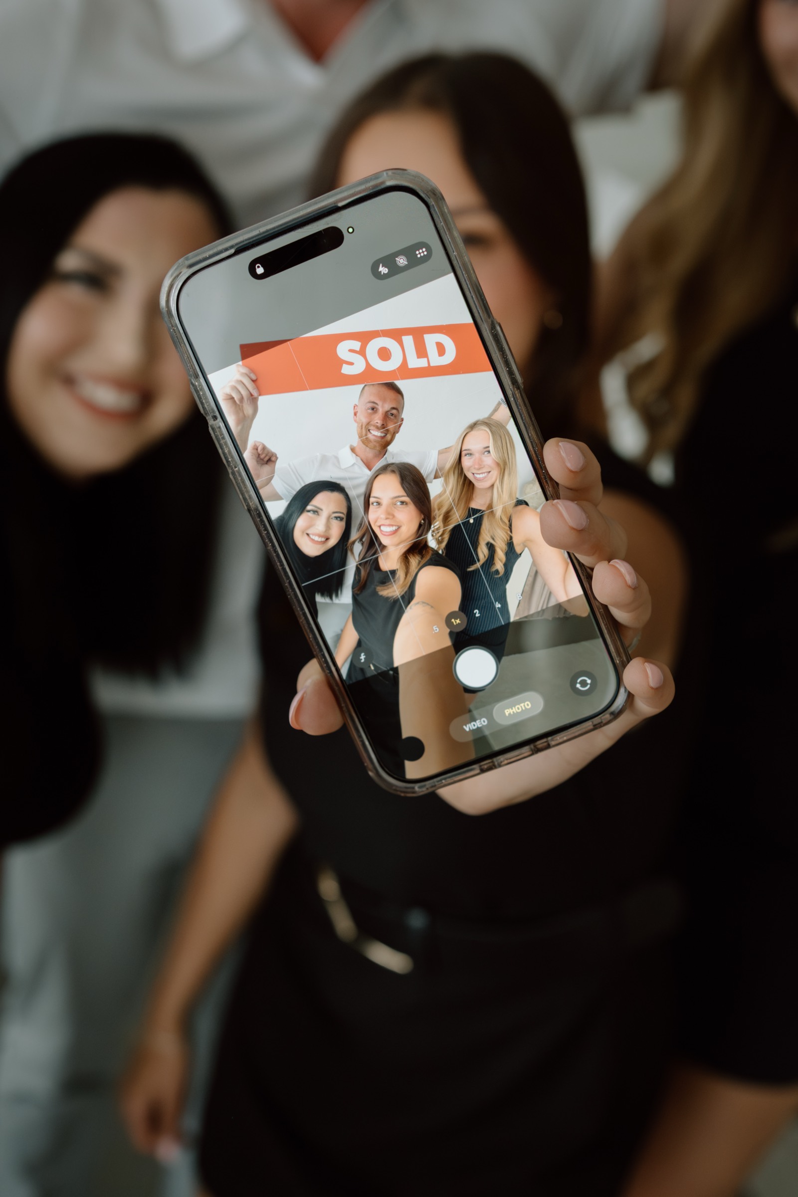 The Knight Group team holding up a phone showing a SOLD listing