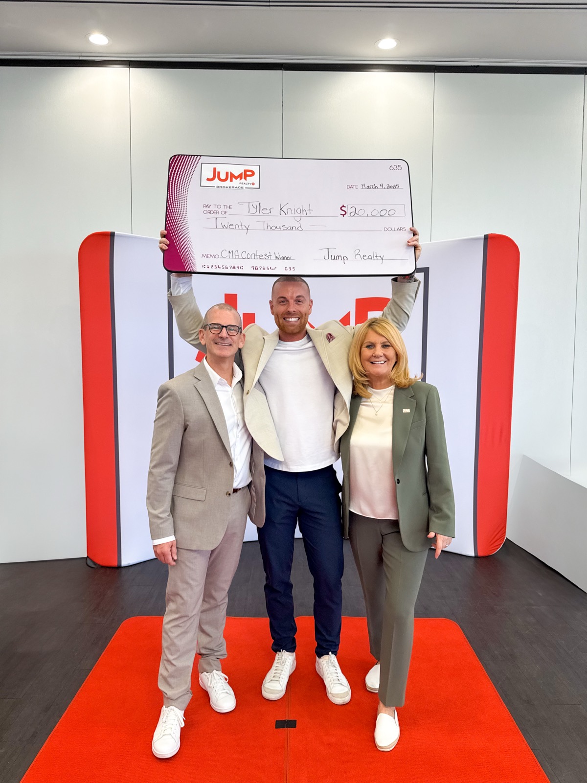 Tyler Knight holding a $20,000 cheque from JUMP Realty, with JUMP owners Damon Winney and Mary Morrison beside him
